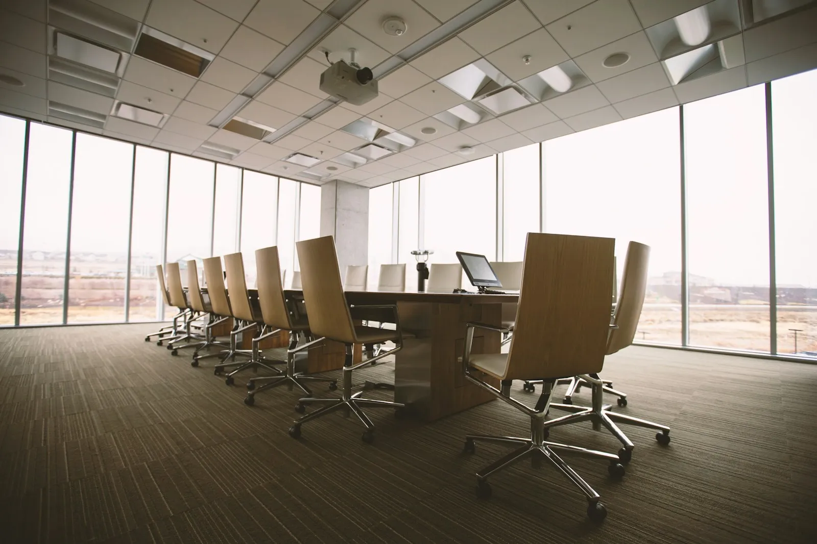 A carpeted boardroom with a conference table and windows